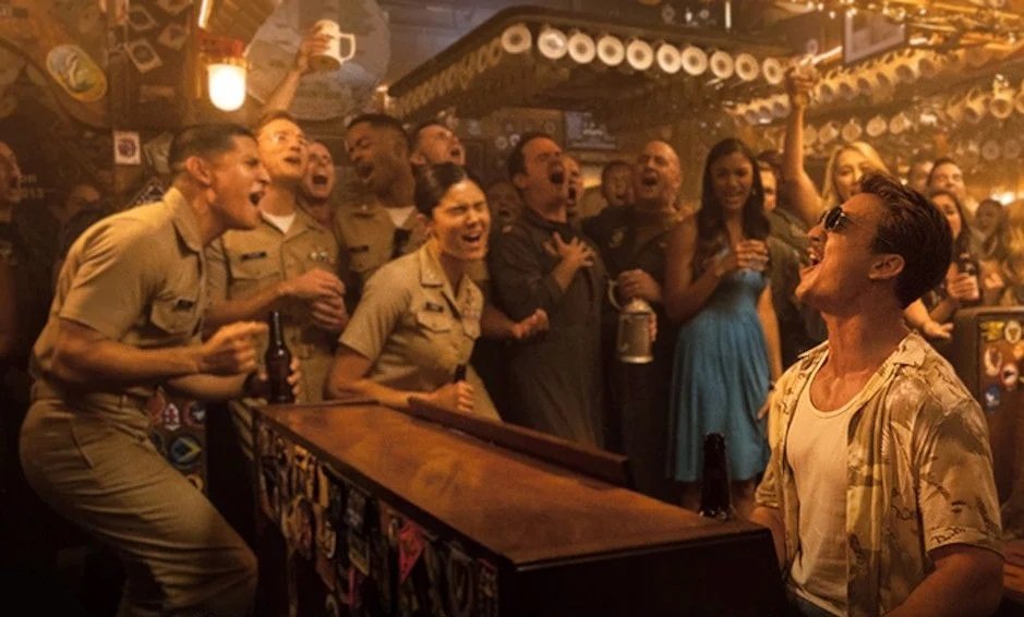 Cena do bar em Top Gun Maverick com personagens reunidos ao redor do piano
