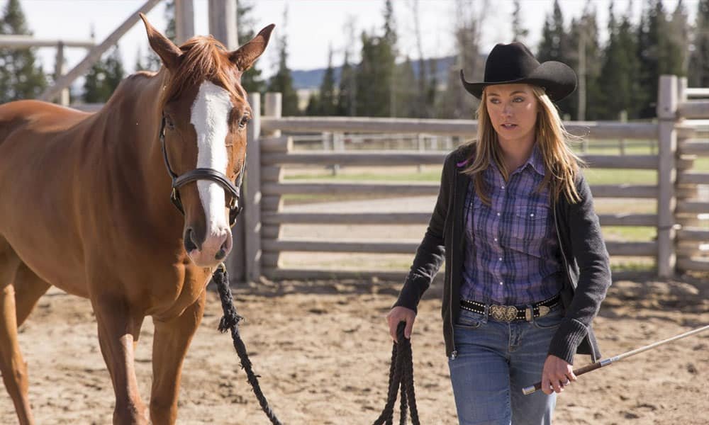 Cena de Heartland com Amy ao lado de um cavalo, representando a conexão da série com os animais e a vida no rancho.