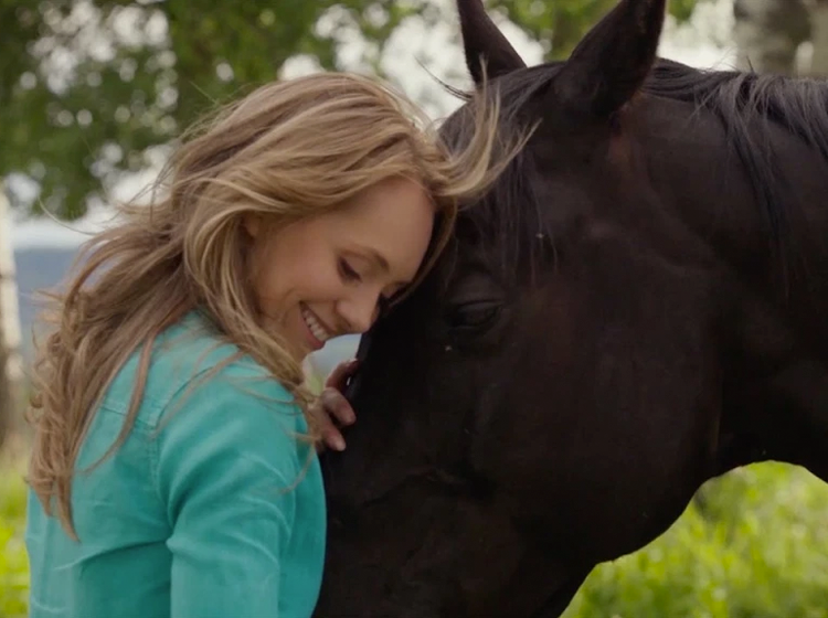 Cena emocionante da série Heartland com Amy abraçando o cavalo Spartan, mostrando a conexão especial da história com os animais.