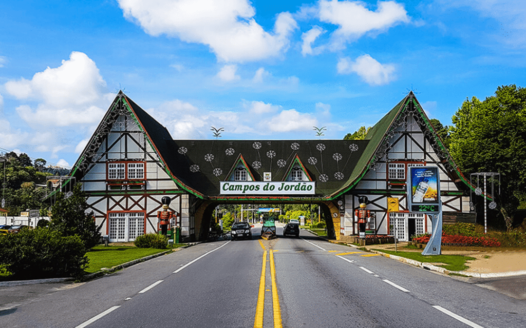 Entrada de Campos do Jordão, com portal e estrada cercada por árvores.