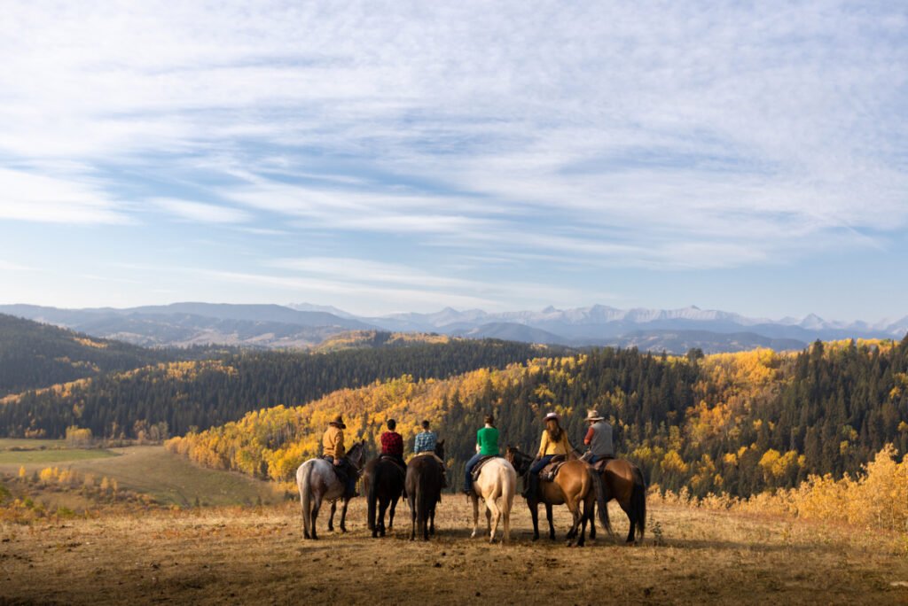 Cavalos da série Heartland em uma paisagem aberta, com montanhas e clima de vida no rancho.