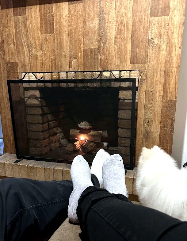 Lareira acesa na Pousada Apple House em Campos do Jordão, com o cachorro Steve descansando ao lado.