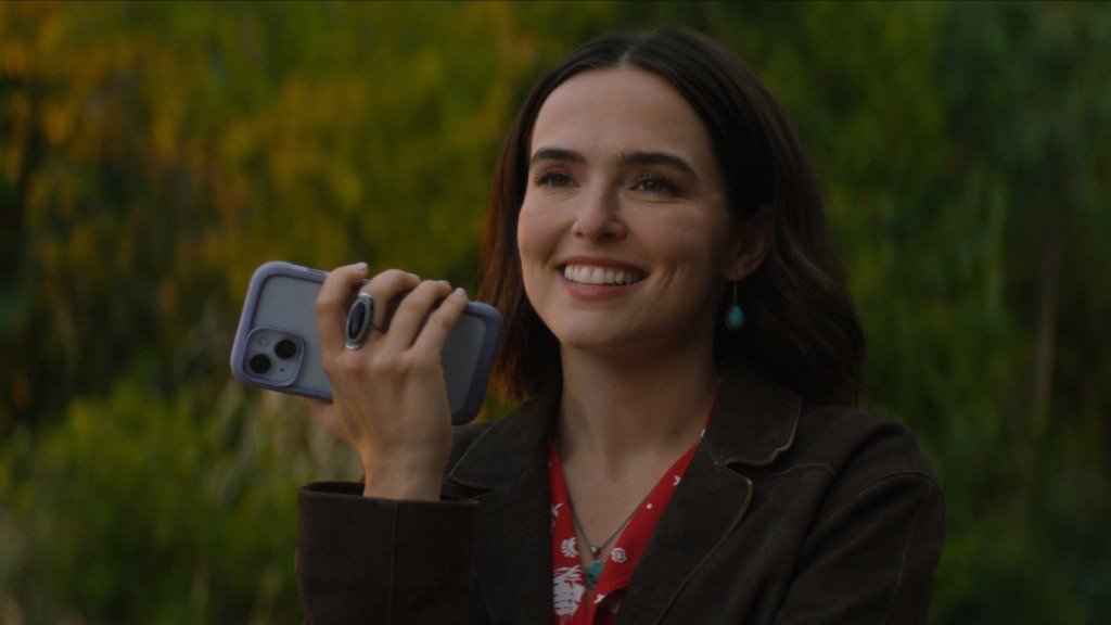 Cena do filme Mensagens para Isabelle, com Jill sorrindo enquanto segura o celular.