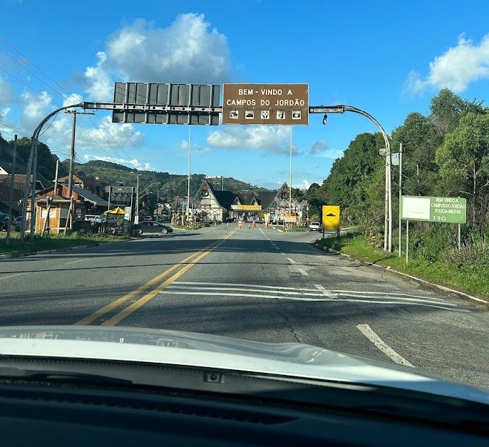 Entrada de Campos do Jordão em viagem em família, com vista da estrada chegando à cidade na Serra da Mantiqueira.