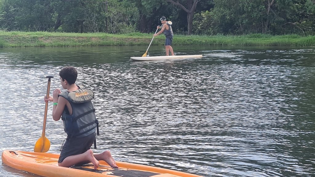Passeio de canoa no lago do Brotas Eco Hotel Fazenda, cercado por uma área verde.