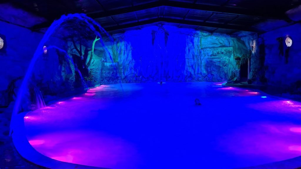Lagoa Encantada do Brotas Eco Hotel Fazenda, com piscina aquecida, cascata e iluminação em tons de azul e rosa.
