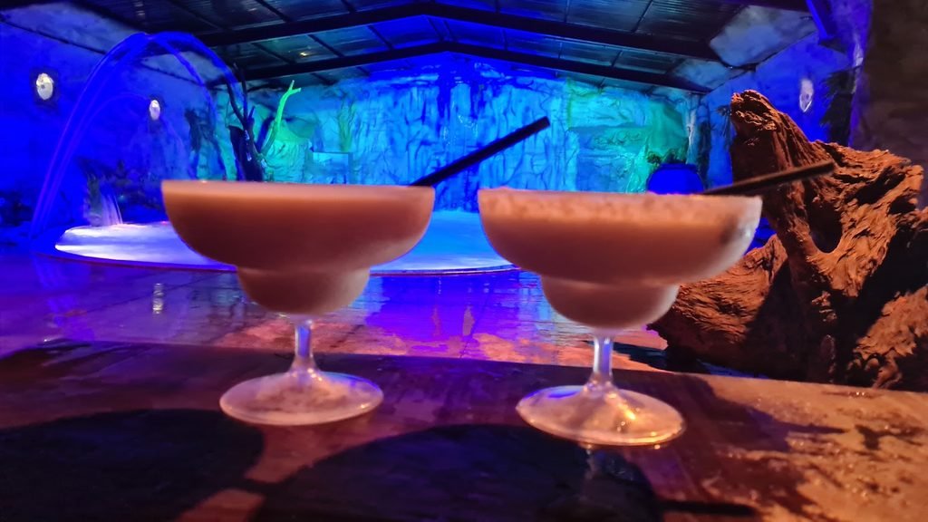 Duas bebidas servidas em taças diante da Lagoa Encantada, no Brotas Eco Hotel Fazenda.