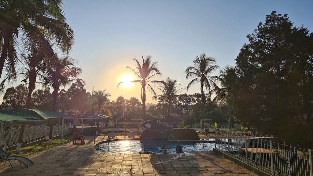 Piscinas externas do Brotas Eco Hotel Fazenda ao entardecer, cercadas por árvores e áreas de descanso.