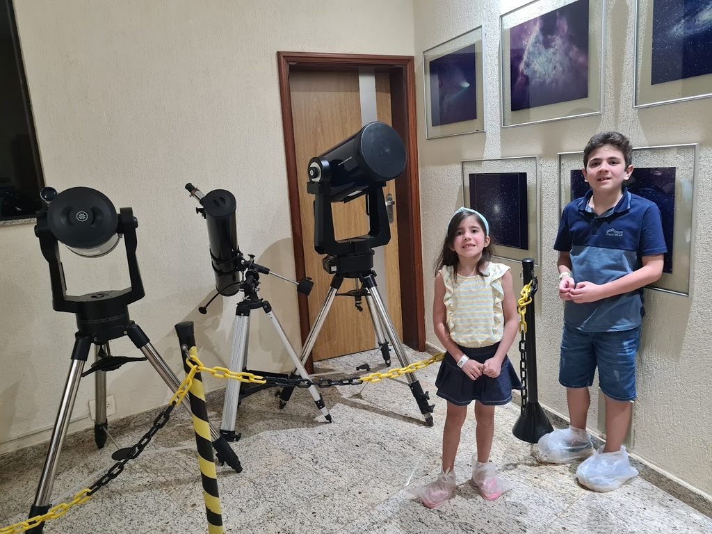 Davi e Amanda ao lado dos telescópios durante a visita ao Centro de Estudos do Universo, em Brotas.
